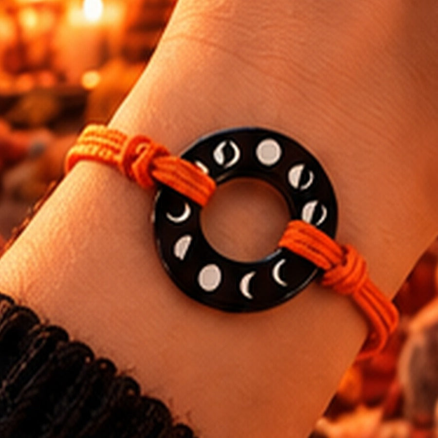 Black ring moon phases bracelet with orange cord and warm fall background