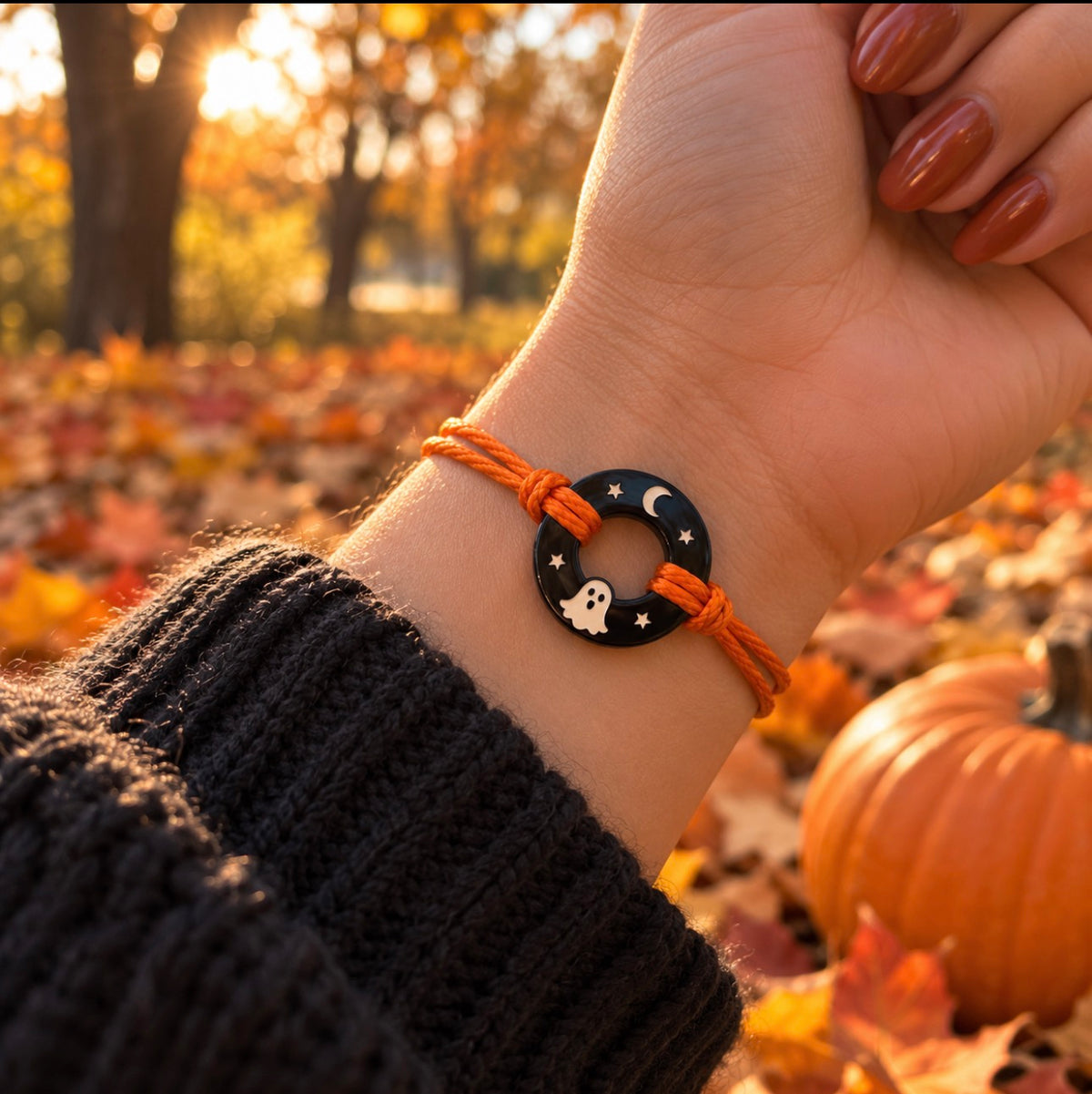 Black onyx Life Token with ghost, moon and star engravings, orange cord at an outdoor pumpkin patch